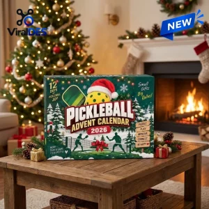 Front view of Pickleball Advent Calendar 2026 on a wooden table with a Christmas tree and fireplace backdrop.