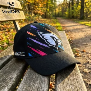 Arizona Cardinals NFL Crucial Catch Black Cap featuring a team logo and multicolored graphic streaks on a wooden bench.
