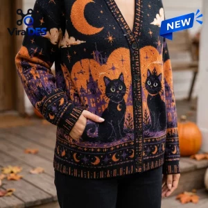 Close-up view of a black cat knit cardigan featuring purple castle silhouettes, orange moons, and gold stars.