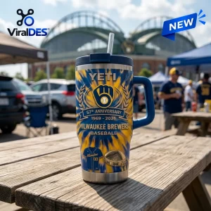Front view of a Milwaukee Brewers 57th Anniversary Stanley Tumbler with blue and yellow tie-dye patterns on a wood table.