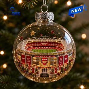 Close-up of a clear glass ball ornament enclosing a miniature stadium model with Christmas trees and lights.