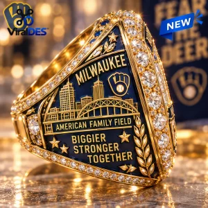 Closeup of a gold championship ring featuring a skyline graphic, the text American Family Field, and embedded crystals.
