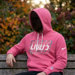 Kansas City Chiefs Crucial Catch pink pullover hoodie with multi-colored lettering and white drawstring on a park bench.