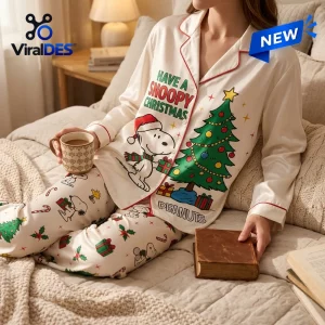 Front view of Snoopy Christmas satin pajamas set worn on a bed holding a mug.