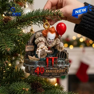 Close-up of a decorative IT 40th Anniversary Pennywise Christmas ornament hanging on a pine tree branch.
