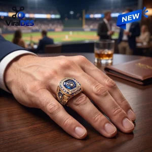 Close-up of a hand wearing a gold Milwaukee Brewers 2026 Championship Ring at a table overlooking a baseball stadium.