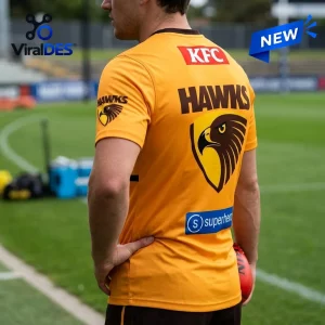 Hawthorn Football Club Gold Performance T-Shirt featuring brown Hawks logo, KFC branding, and sponsor prints on a field.