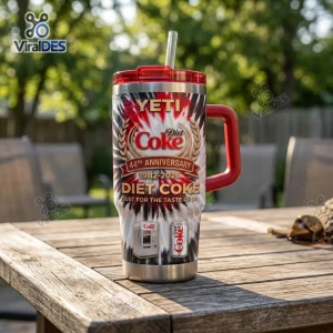 Front view of YETI Diet Coke 44th Anniversary Handle Tumbler on a wooden table outdoors.