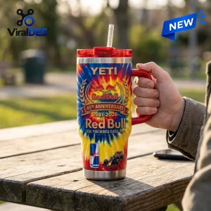 Hand holding Red Bull 45th Anniversary YETI Handle Tumbler on outdoor wooden table.
