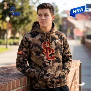 Man wearing a USC Trojans camo hoodie standing outdoors near a brick wall.