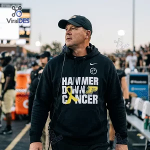 Man wearing Purdue Boilermakers Hammer Down Cancer Black Hoodie on a football field.