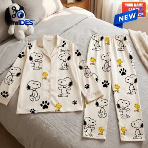 Top view of a personalized Snoopy cartoon satin pajama set laid flat on a bed.