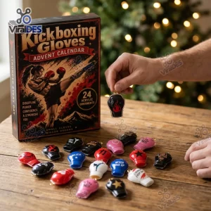 Hand holding a miniature boxing glove ornament next to a Kickboxing Gloves Acrylic Christmas Advent Calendar box on a wooden table.