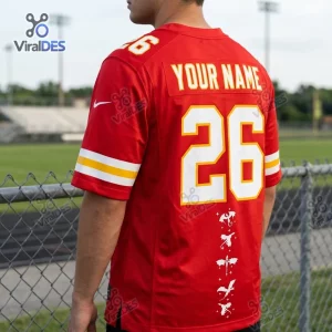 Rear view of a red custom football jersey featuring white numbering 26 and dragon graphics on an outdoor field.