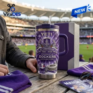 Front view of a purple Fremantle Dockers 32nd Anniversary YETI Tumbler with a straw sitting on a wooden table at a stadium.