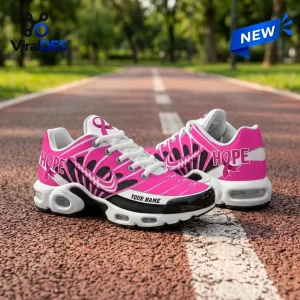 Side view of pink sneakers featuring hope text and ribbons on a running track.