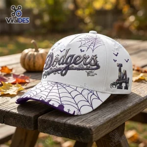 Front view of a white Halloween baseball cap featuring a spiderweb brim and gothic script on a wooden table.