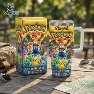 Front view of a Pokemon 30th Anniversary 1996-2026 Tumbler Cup with matching yellow gift box on a wooden picnic table.