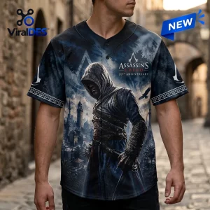 Front view of a person wearing an Assassin's Creed 20th Anniversary baseball jersey with a hooded figure and city graphic.