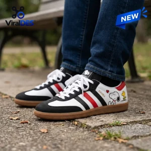 Side angle of Snoopy x Woodstock Leather Samba Sneakers worn outdoors with blue jeans.