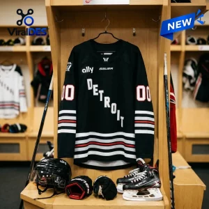 Front view of a black PWHL Detroit 2026 personalized hockey jersey hanging in a locker room.