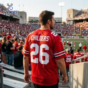 Rear view of a fan wearing a red football jersey with Childers 26 on the back inside a crowded stadium.