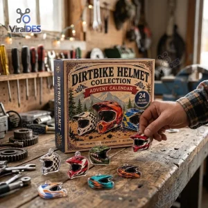 A hand places a mini helmet ornament on a wooden workbench featuring the Dirt Bike Helmet Christmas Advent Calendar 2026 box.