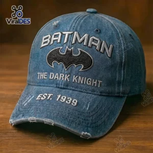 Front view of a blue Batman Dark Knight distressed baseball cap with embroidered text on a wooden surface.