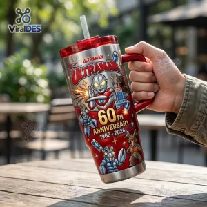 Hand holding an Ultraman 60th Anniversary 1966-2026 Tumbler Cup outdoors on a wooden table.