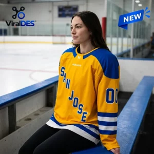 Woman wearing yellow and blue PWHL San Jose 2026 Limited Edition Jersey sitting on a hockey bench.