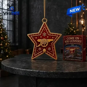 Front view of a red star ornament with gold trim and a cannon icon, next to an advent calendar box on a table.