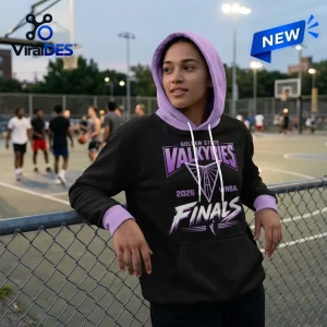 Woman wearing a black and purple Golden State Valkyries 2026 Finals hoodie leaning on a chain-link fence.