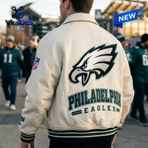 Back view of a person wearing a cream varsity jacket with an eagle logo and green lettering.