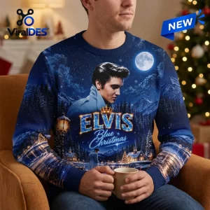 Front view of a man holding a mug while wearing an Elvis Presley Blue Christmas ugly sweater with a winter village scene.
