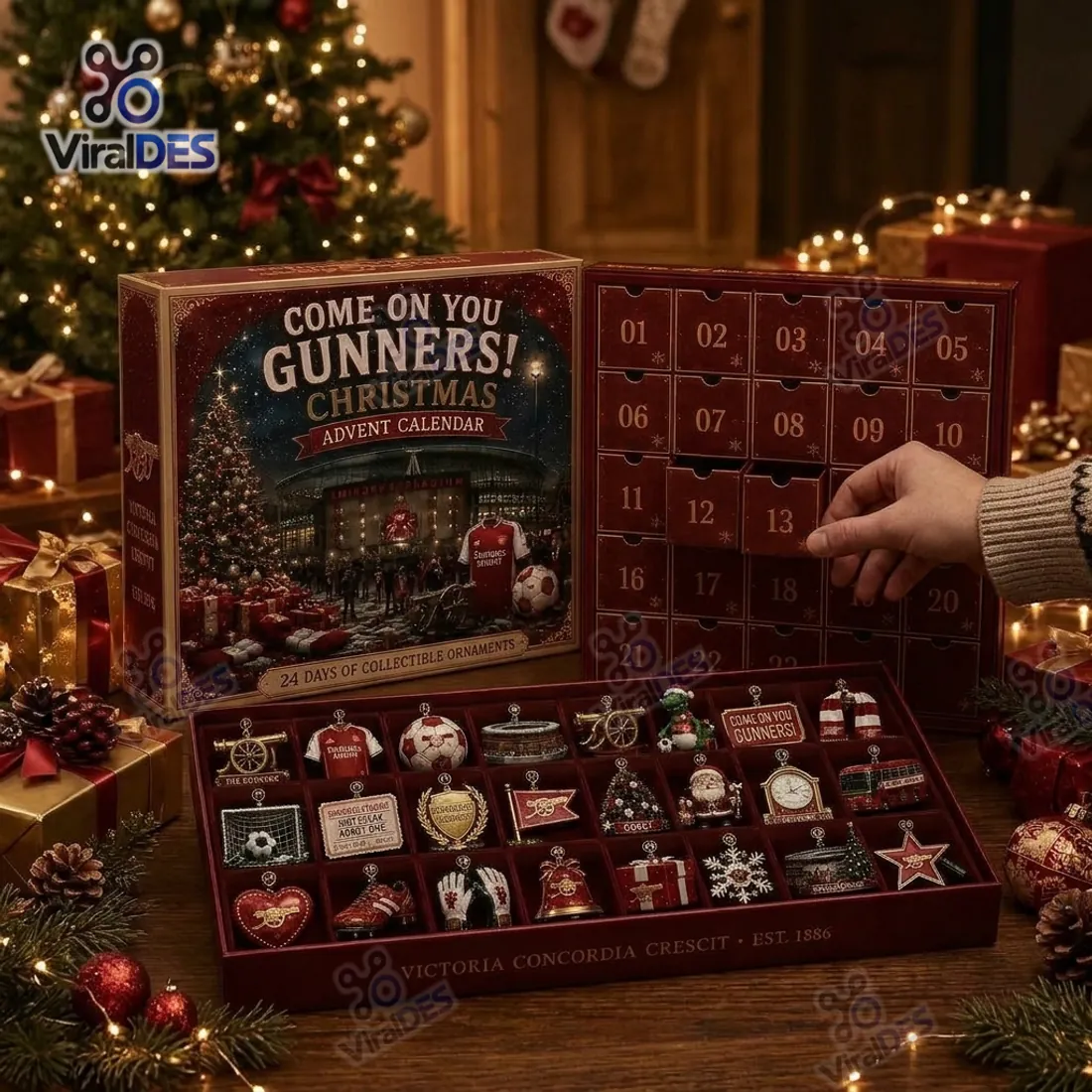 Hand opening numbered compartments 12 and 13 of the Arsenal Christmas Advent Calendar 2026 above the 24 molded 3D Gunners ornaments