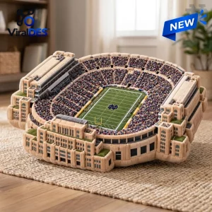 Angled view of a Notre Dame Fighting Irish plush stadium pillow shaped like a football arena on a rug.