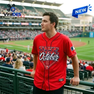 Man wearing the Cleveland Guardians 2026 Postseason Red Baseball Jersey while leaning on a stadium railing.