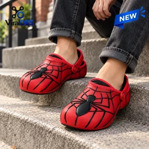 Close-up of red spider web black clogs worn with dark jeans on outdoor stone steps.