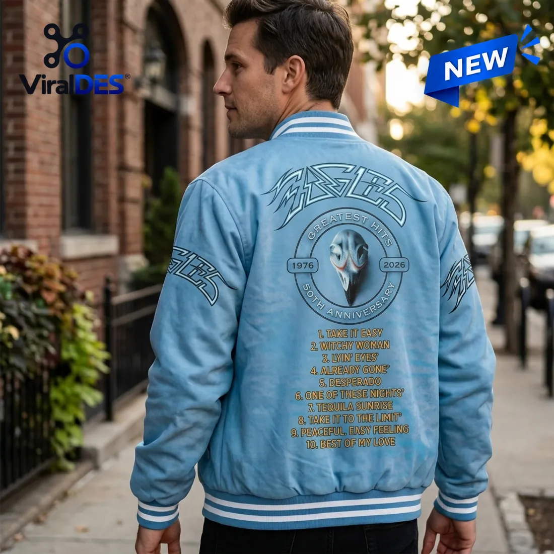 Rear view of a man wearing the Eagles 50th Anniversary Blue Varsity Jacket outdoors in a city setting.