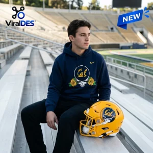 Man wearing a California Golden Bears Grateful Dead hoodie while sitting on stadium bleachers next to a yellow helmet.