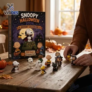 Front view of the Snoopy Peanuts Halloween 2026 Advent Calendar box alongside small themed character figurines on a wooden table.