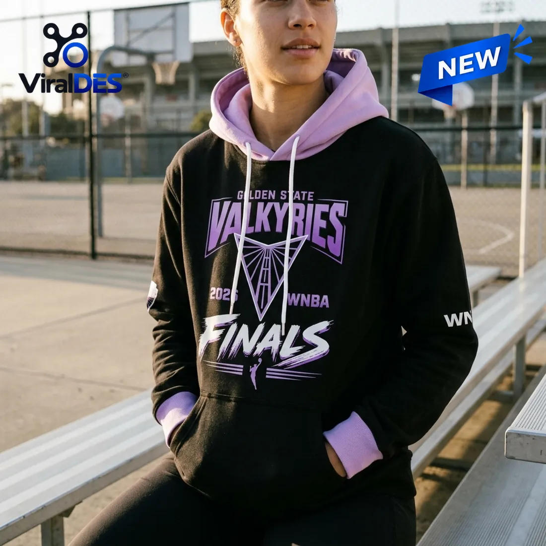 Front view of a person wearing a black and purple hoodie with Golden State Valkyries 2026 Finals graphics sitting on a bleacher.