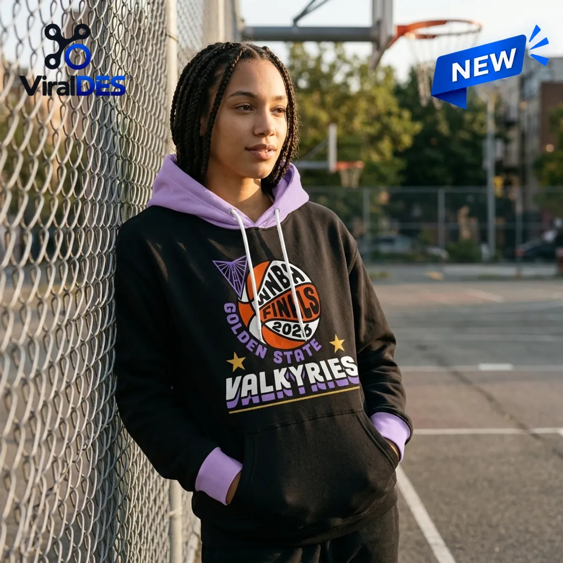 Woman leaning against a basketball court chain-link fence wearing the Golden State Valkyries 2026 WNBA Finals Pullover with hands in the kangaroo pocket