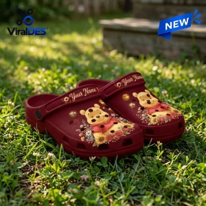 Maroon custom Winnie the Pooh sunflower clogs sitting outdoors on green grass.