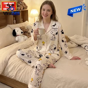 Front view of woman wearing personalized cartoon satin pajama set holding a mug in a bedroom.