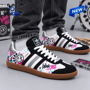 Side view of Blink-182 Smiley Adidas Samba Shoes featuring pink graffiti art and white laces on feet.