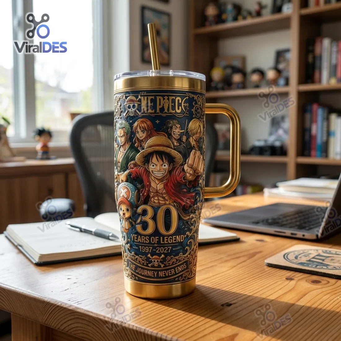 One Piece 30th Anniversary Gold Stanley Tumbler Cup on a wooden study desk beside a notebook and laptop