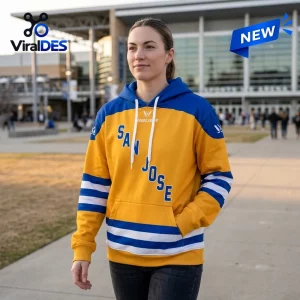 Woman wearing gold and blue hoodie with San Jose text, standing outside a building.