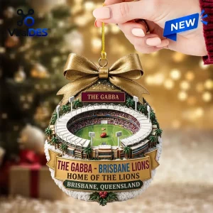 Close-up of Brisbane Lions The Gabba Stadium Christmas Ornament held by a hand against a blurred holiday background.