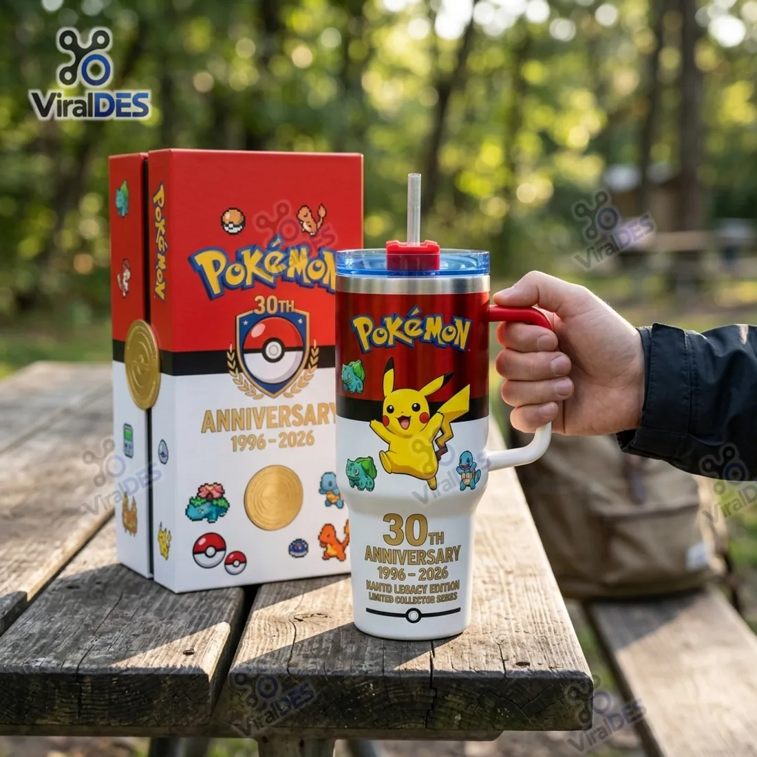 Pokemon 30th Anniversary 40oz Stanley Tumbler held beside its red and white collector box with gold Poke Ball medallion and pixel sprites